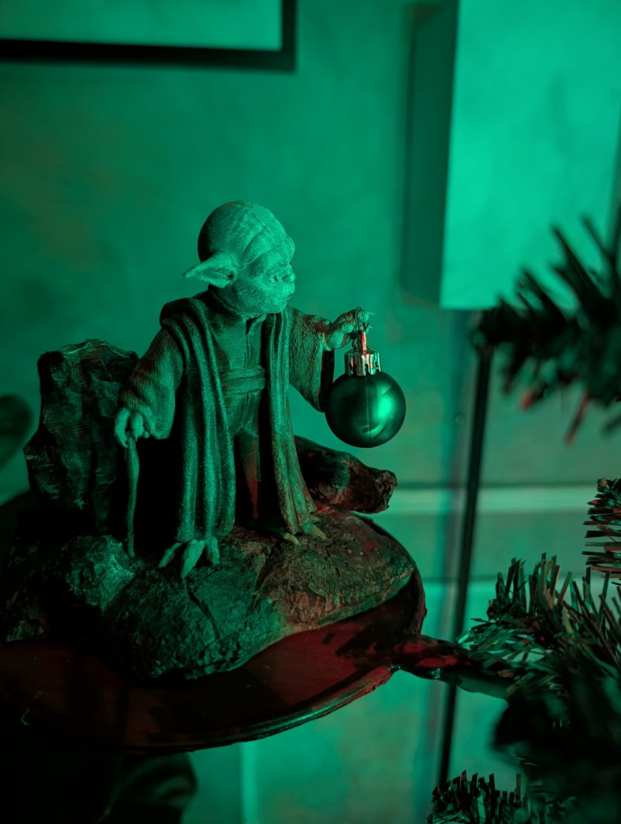 Yoda on a floating tree platform in green light, hanging a green Christmas ornament