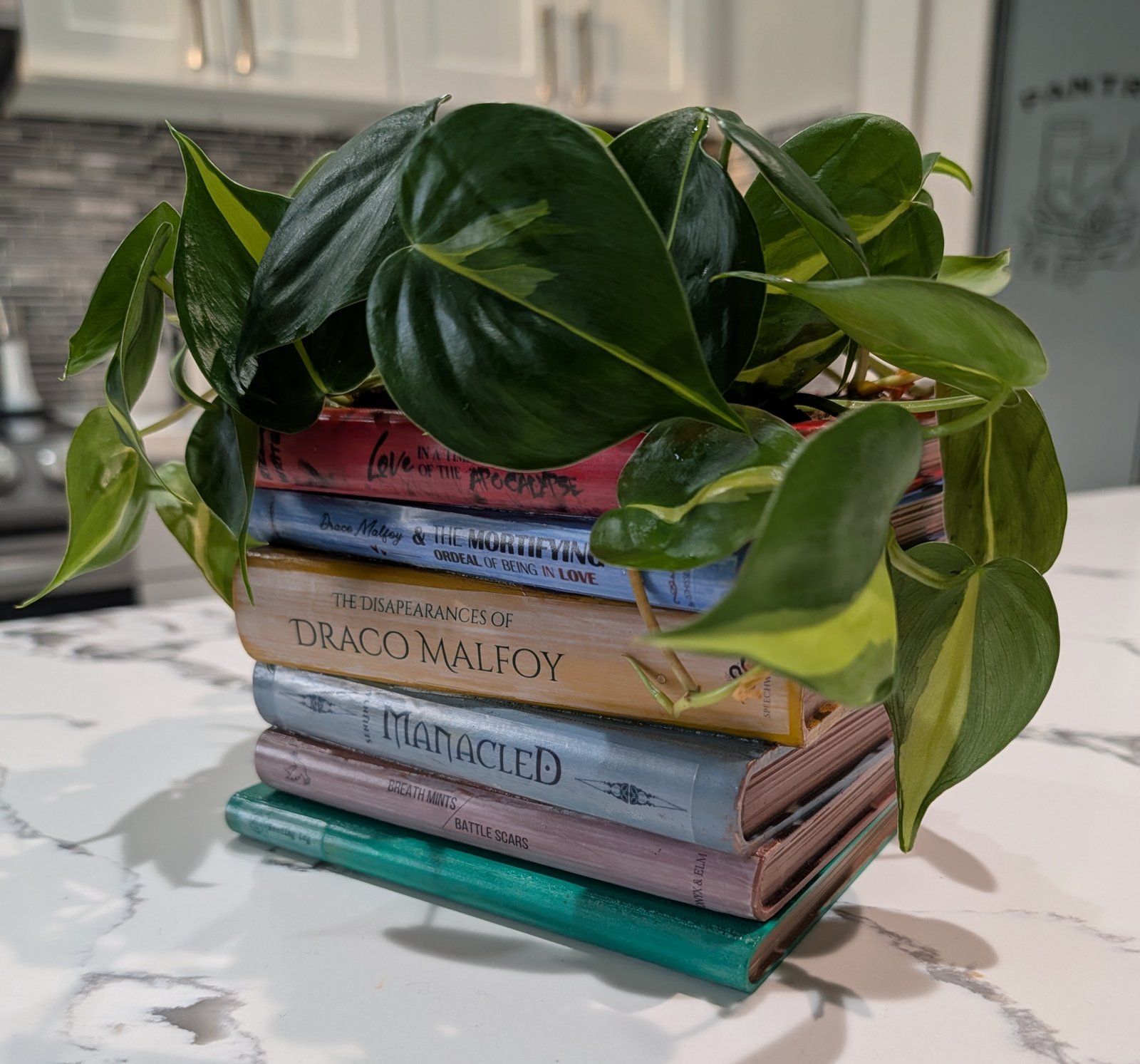 A second book-stack planter, fully overgrown with a large pothos plant